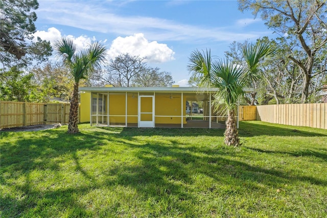 back of house featuring a lawn, a fenced backyard, and a sunroom