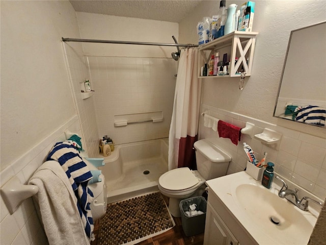 bathroom featuring toilet, a textured ceiling, vanity, a shower stall, and tile walls