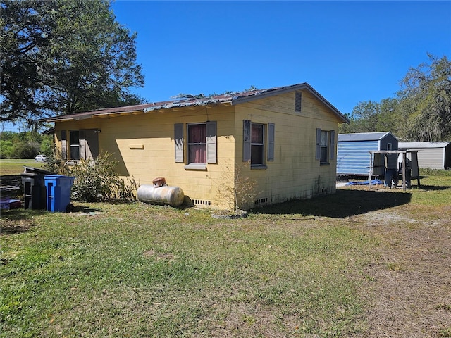 view of property exterior featuring an outbuilding, a yard, and crawl space