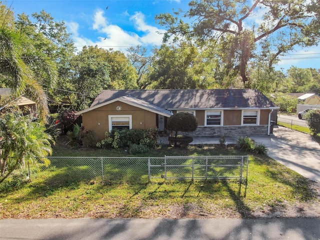 ranch-style house with stone siding, driveway, a fenced front yard, and stucco siding