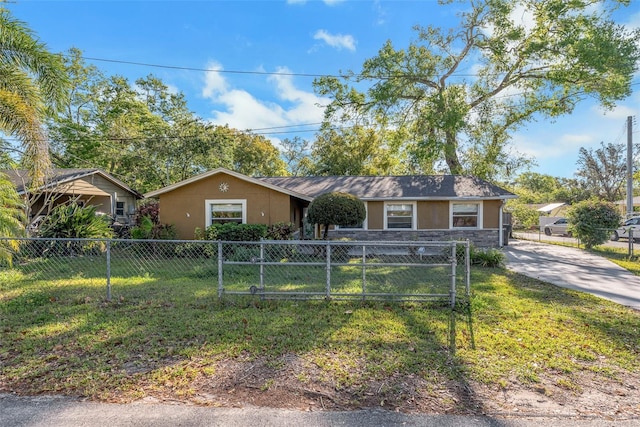 view of front of house featuring a gate, stucco siding, a front lawn, stone siding, and a fenced front yard