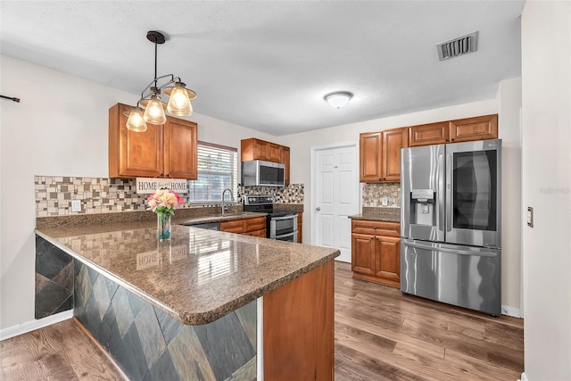 2412 Giddens Ave, Seffner, FL 33584 - kitchen featuring stainless steel appliances, dark countertops, brown cabinetry, a peninsula, and dark wood-style floors