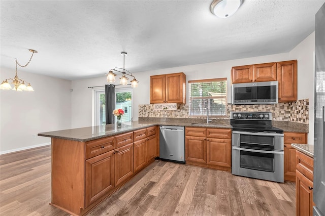 2412 Giddens Ave, Seffner, FL 33584 - kitchen with stainless steel appliances, brown cabinetry, plenty of natural light, tasteful backsplash, and a textured ceiling