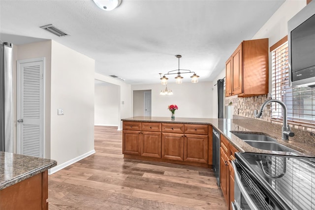 2412 Giddens Ave, Seffner, FL 33584 - kitchen featuring brown cabinetry, a peninsula, appliances with stainless steel finishes, and light wood-style flooring