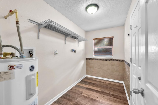 2412 Giddens Ave, Seffner, FL 33584 - laundry area with water heater, tile walls, a textured ceiling, wood finished floors, and wainscoting
