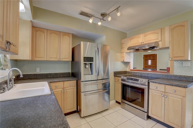 kitchen featuring light brown cabinets, under cabinet range hood, a sink, appliances with stainless steel finishes, and dark countertops