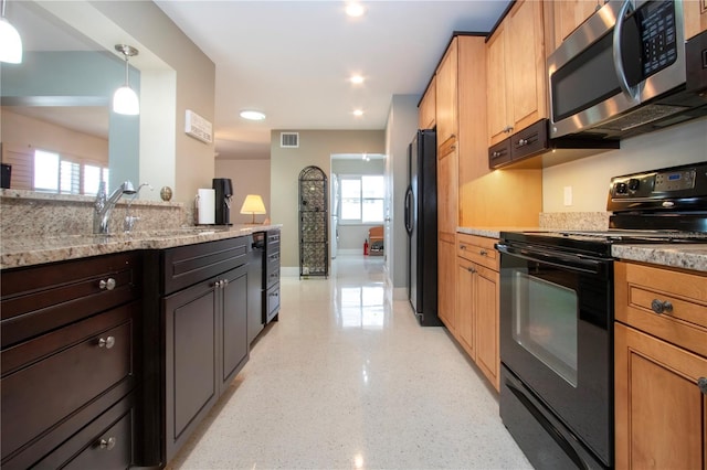 kitchen featuring baseboards, visible vents, light stone countertops, black appliances, and a sink