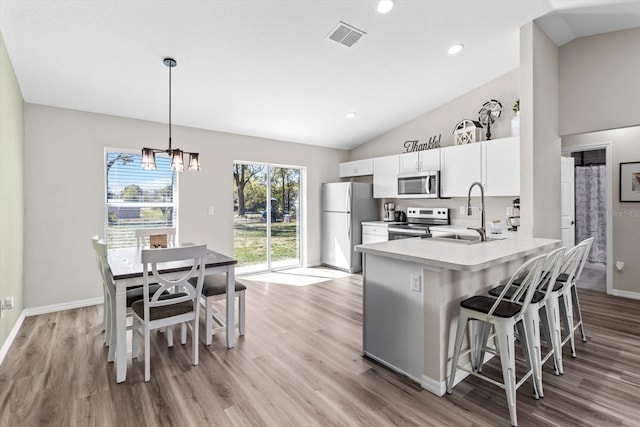 kitchen with lofted ceiling, stainless steel appliances, a breakfast bar, a sink, and visible vents