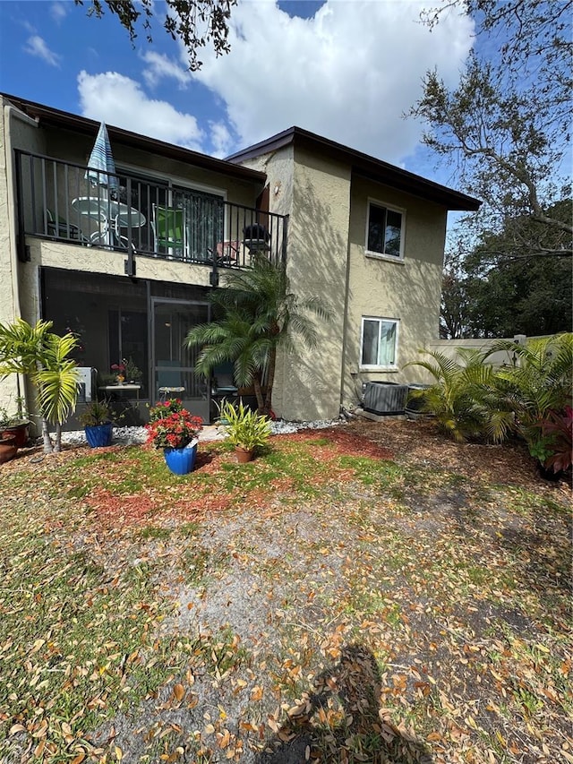 back of property with a balcony, central AC, and stucco siding