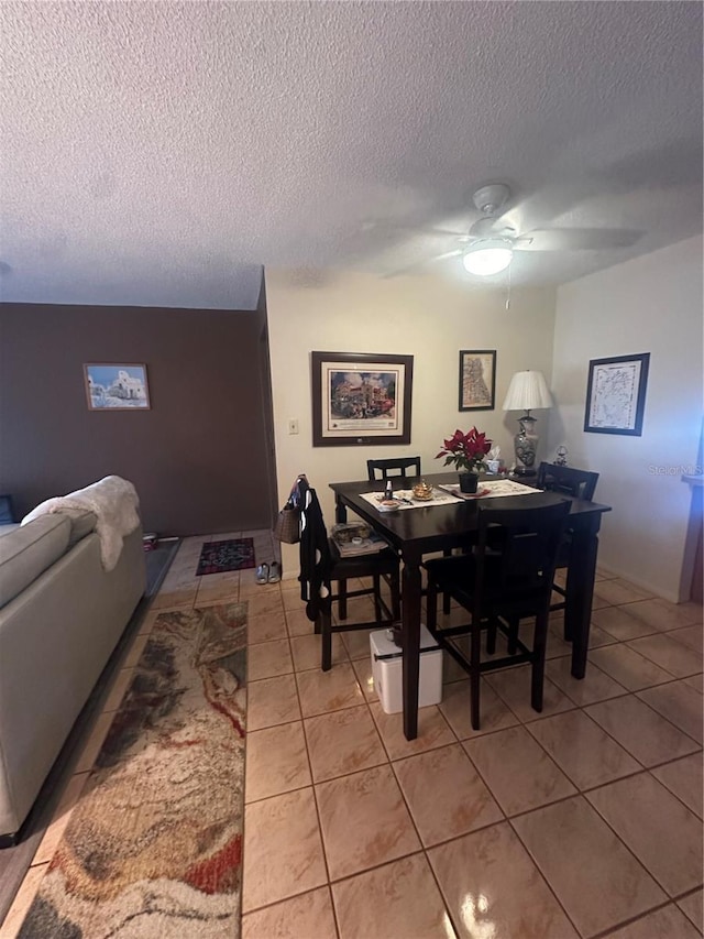 dining space with a textured ceiling, light tile patterned flooring, and a ceiling fan