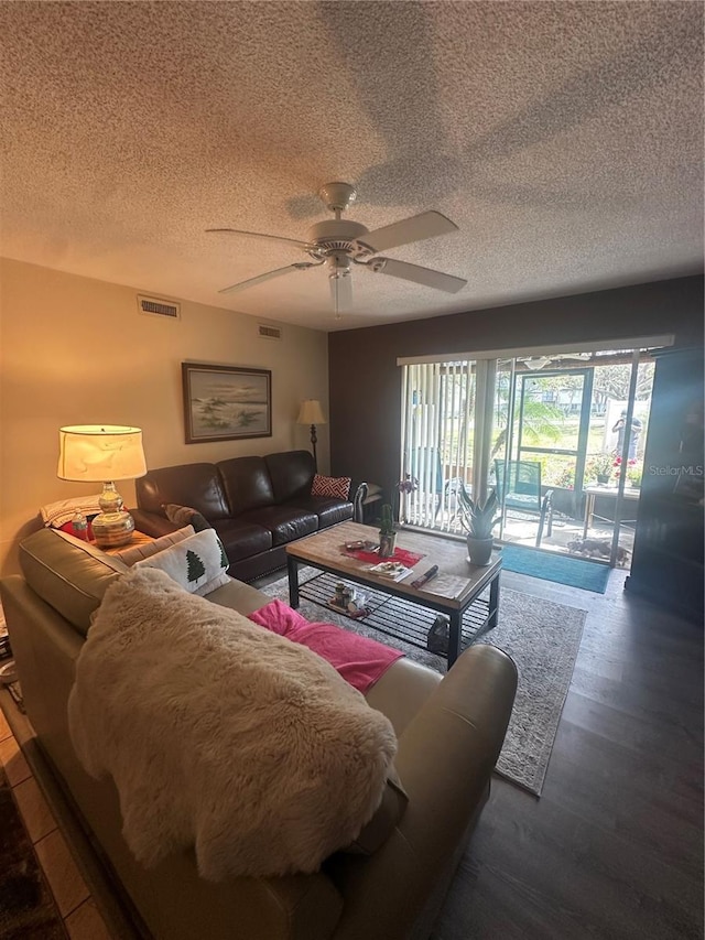 living area with a ceiling fan, visible vents, a textured ceiling, and wood finished floors