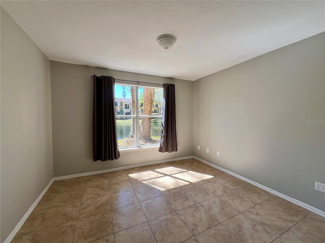 tiled spare room featuring baseboards