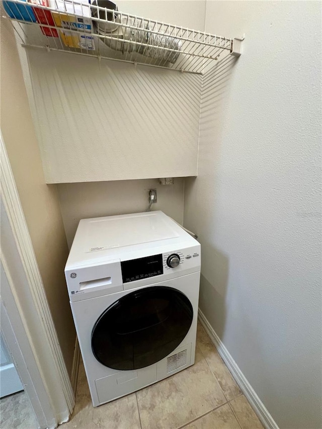 clothes washing area featuring washer / dryer, laundry area, baseboards, and light tile patterned floors