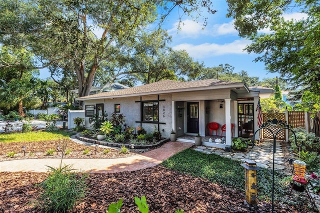 view of front of house featuring fence, roof with shingles, and stucco siding