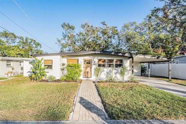 mid-century inspired home with concrete driveway, an attached carport, fence, a front lawn, and brick siding