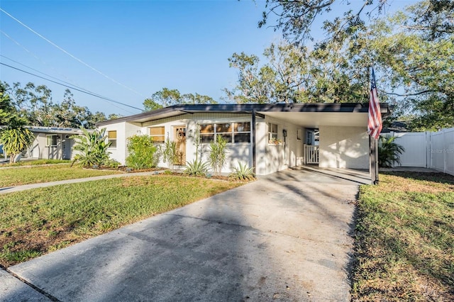 mid-century modern home featuring a carport, a front lawn, concrete driveway, and fence