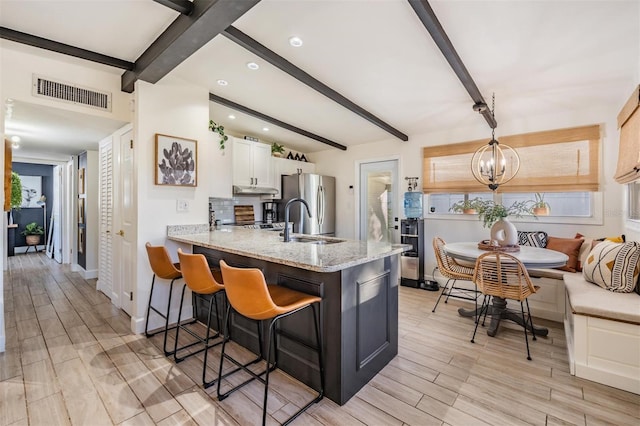 kitchen with wood finish floors, visible vents, white cabinets, freestanding refrigerator, and breakfast area