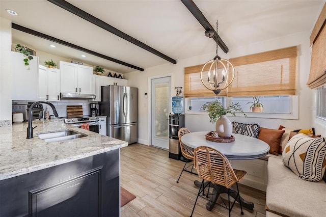 kitchen featuring tasteful backsplash, breakfast area, stainless steel appliances, under cabinet range hood, and a sink