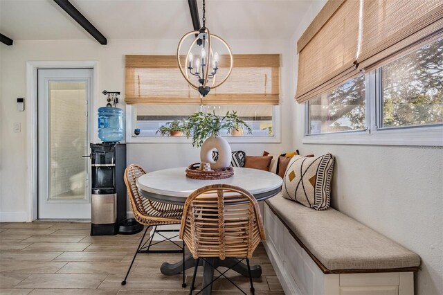 dining area with wood finish floors, breakfast area, beam ceiling, and an inviting chandelier