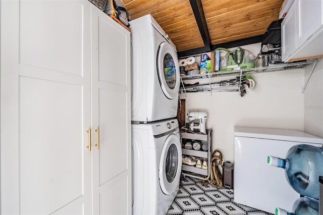 laundry area with wooden ceiling, cabinet space, and stacked washer / drying machine