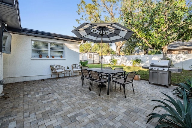 view of patio / terrace featuring area for grilling, a fenced backyard, an outbuilding, a storage unit, and outdoor dining space