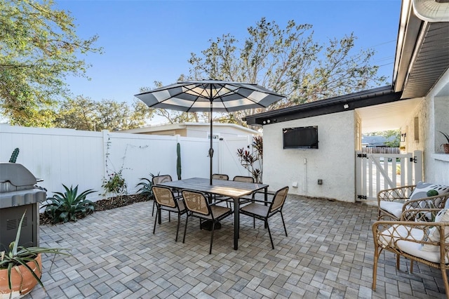 view of patio / terrace with outdoor dining space, a fenced backyard, and a gate