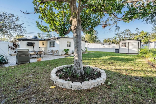 view of yard featuring a patio area, a shed, a fenced backyard, and an outbuilding