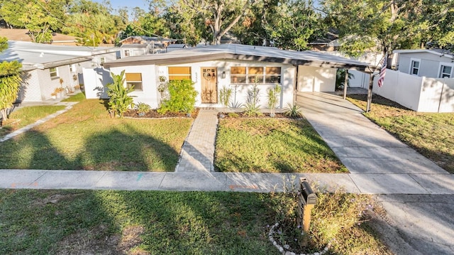 view of front facade featuring concrete driveway, a front yard, and fence