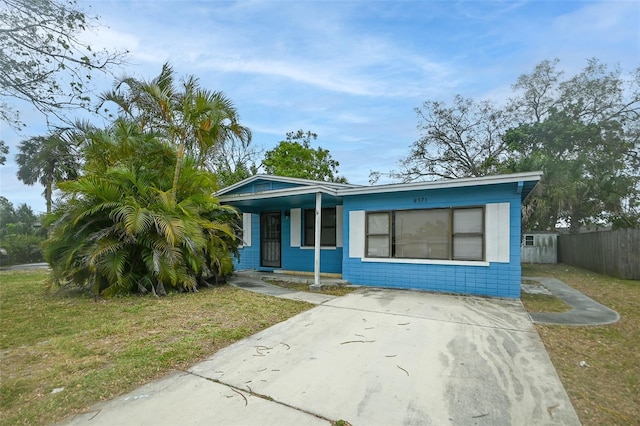 bungalow with covered porch, concrete block siding, a front lawn, and fence