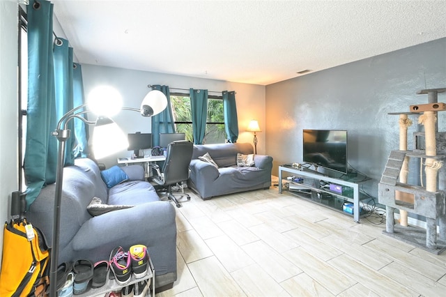 living room featuring a textured wall, visible vents, and a textured ceiling