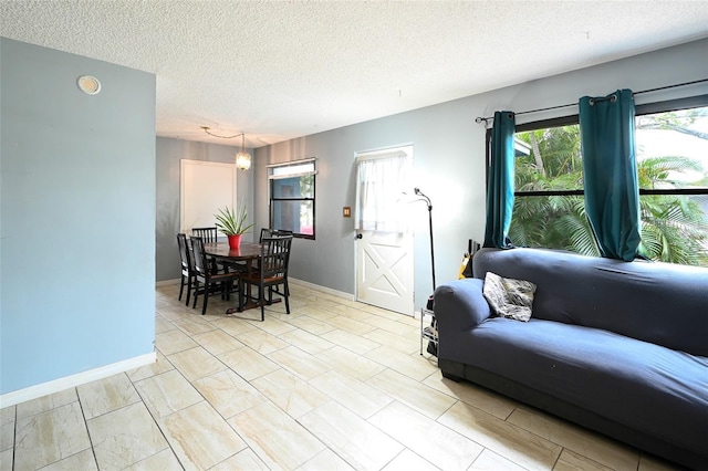 living area featuring a textured ceiling and baseboards