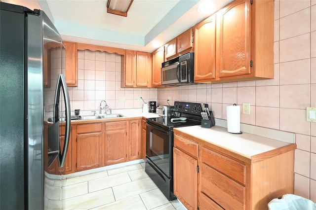 kitchen featuring a sink, decorative backsplash, light countertops, black range with electric stovetop, and stainless steel refrigerator with ice dispenser