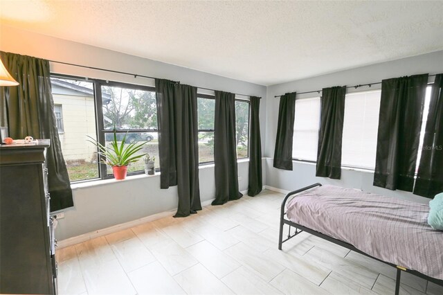 bedroom with baseboards, multiple windows, and a textured ceiling