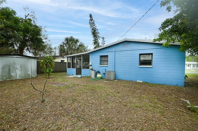 rear view of house with central air condition unit, fence, and a sunroom