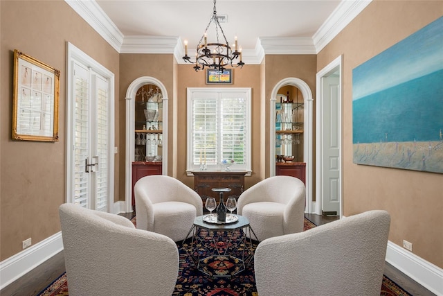 sitting room featuring ornamental molding, dark wood-style flooring, baseboards, and an inviting chandelier