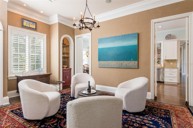 living area featuring baseboards, wood finished floors, a notable chandelier, and ornamental molding