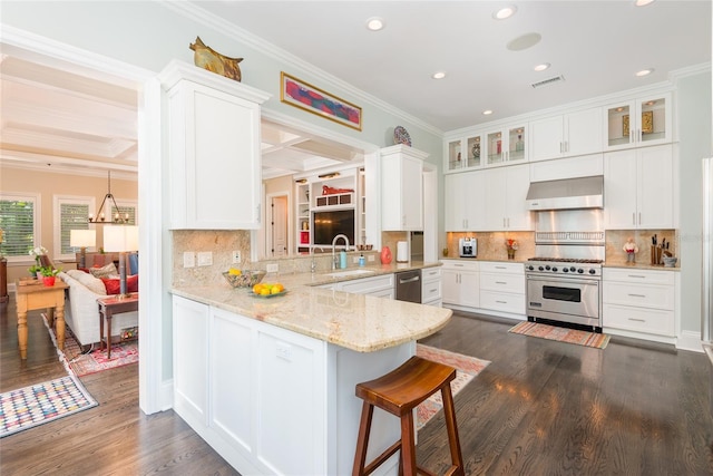 kitchen featuring a sink, appliances with stainless steel finishes, wall chimney range hood, ornamental molding, and glass insert cabinets