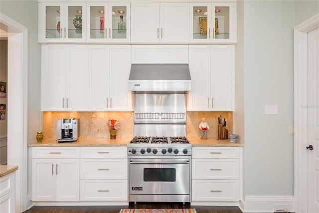 kitchen featuring wall chimney range hood, designer range, light stone counters, and white cabinets