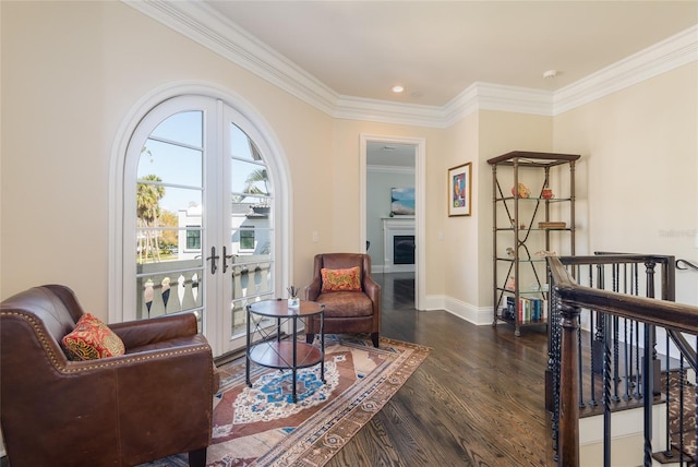 living area featuring dark wood-style flooring, an upstairs landing, ornamental molding, french doors, and a glass covered fireplace