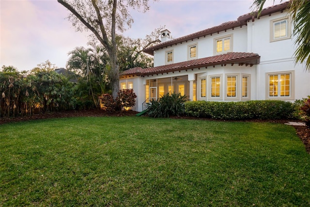 rear view of house featuring a lawn, a chimney, and stucco siding