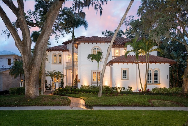 mediterranean / spanish-style home featuring a front yard, a tiled roof, and stucco siding