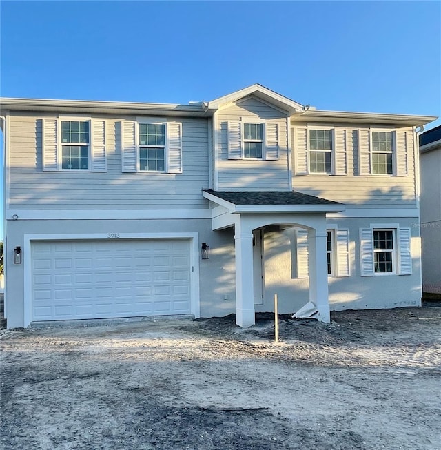 view of front of property with an attached garage, driveway, and stucco siding