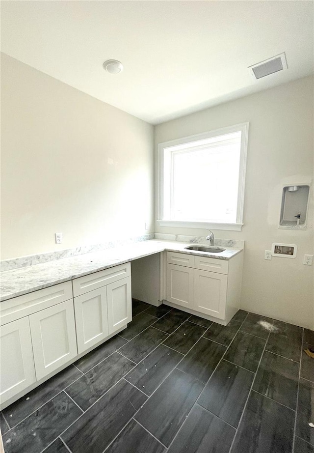 laundry area with washer hookup, cabinet space, a sink, and visible vents