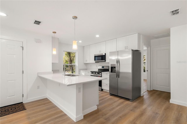 kitchen featuring appliances with stainless steel finishes, visible vents, a sink, and a peninsula