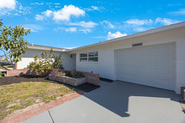 ranch-style home featuring a garage, concrete driveway, and stucco siding