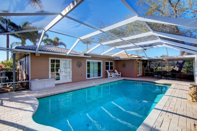 outdoor pool with a patio, french doors, and glass enclosure