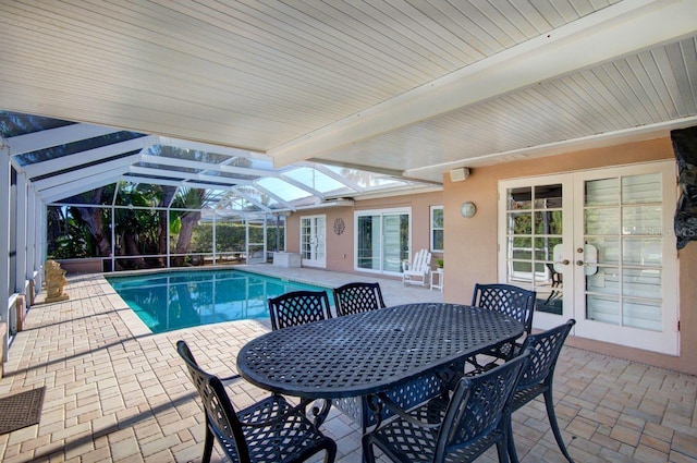 pool with glass enclosure, french doors, a patio area, and outdoor dining area