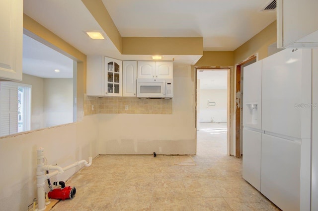 kitchen with white appliances, visible vents, white cabinets, decorative backsplash, and glass insert cabinets