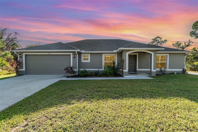 single story home with an attached garage, driveway, a front yard, and stucco siding