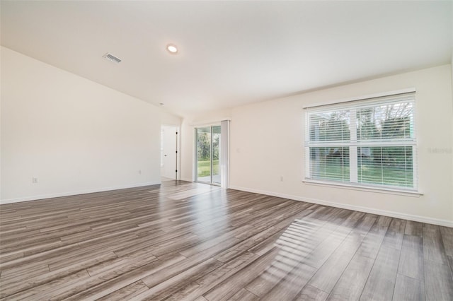 unfurnished room with a wealth of natural light, visible vents, baseboards, and wood finished floors